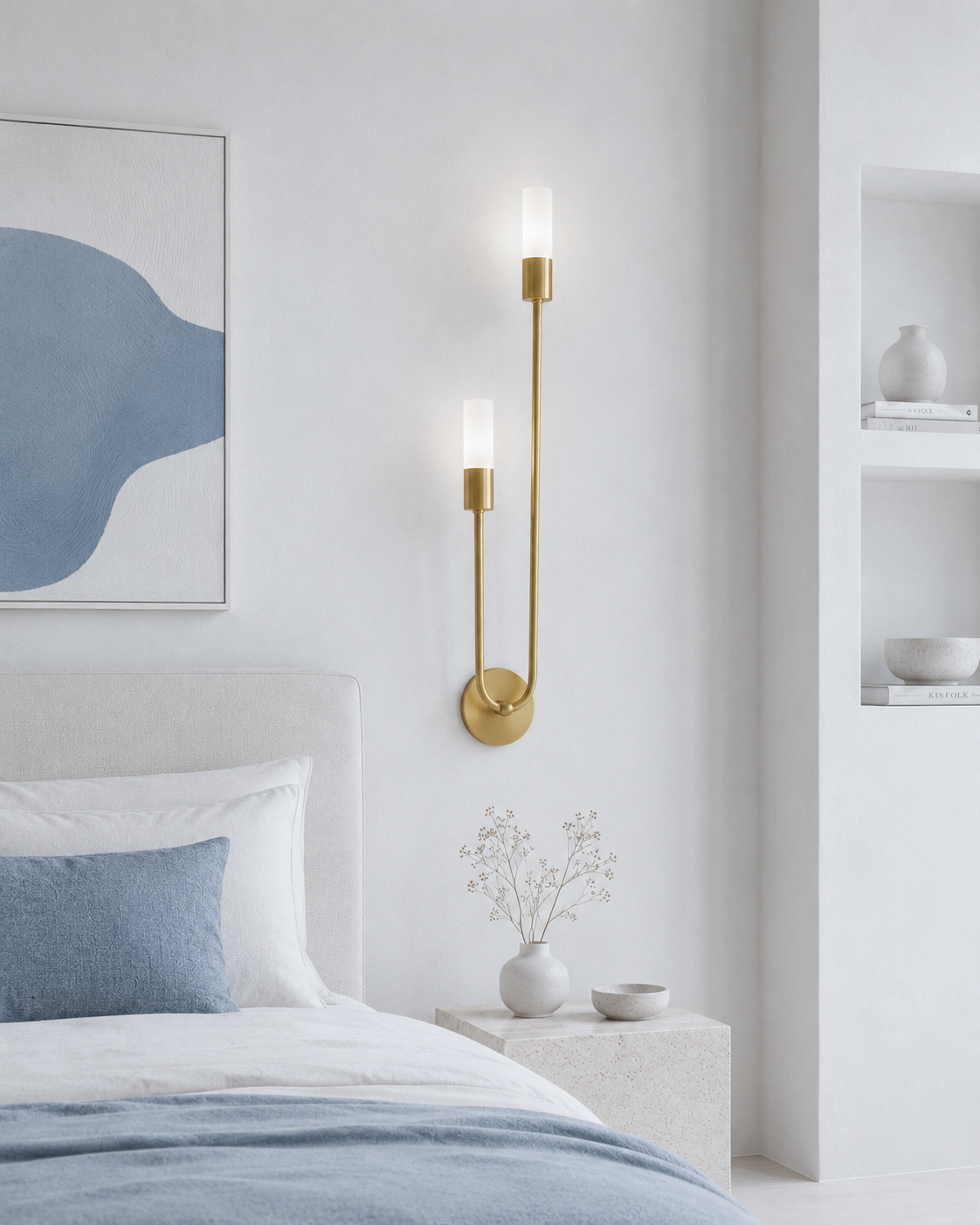 A modern wall-mounted sconce with two vertical frosted glass shades and a curved gold metal frame, shown lit in a minimalist bedroom setting.
