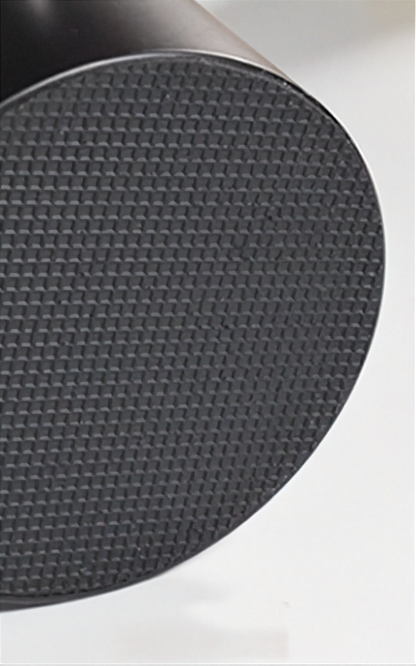 Close-up of a black textured circular disc with a fine woven or grid-like surface, shown against a white background.