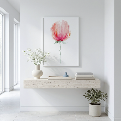A framed watercolor art print of a pink and red tulip hanging on a white wall above a floating stone console table in a bright, modern room.