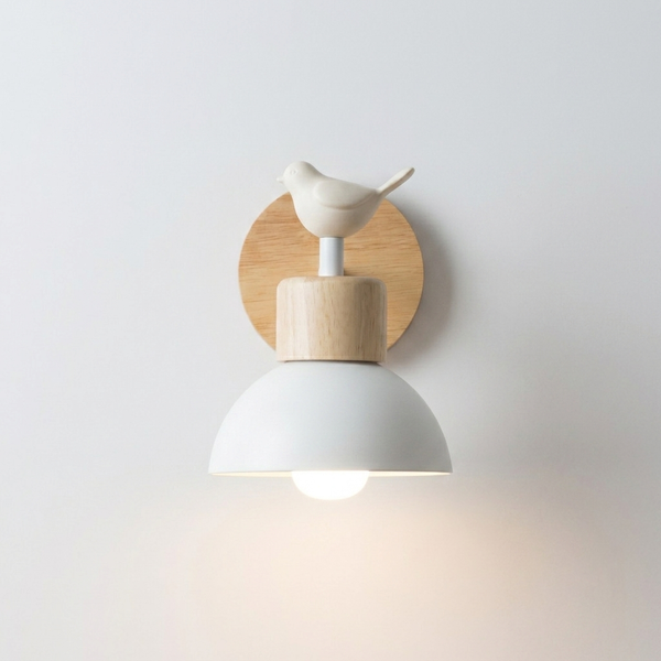 A modern wall-mounted bird-shaped light fixture with a white dome shade, light wood accents, and a small white bird on a circular wood backplate, shown against a plain light gray wall.