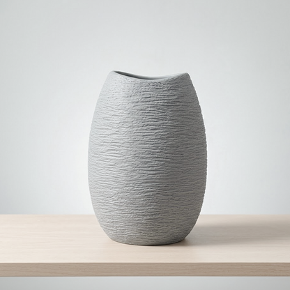 A light gray textured ceramic vase with a small slant cut on the rim, displayed on a light wood surface against a neutral light gray background.