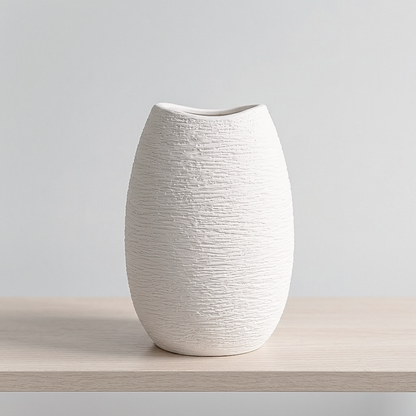 A small textured ceramic vase in off-white, standing on a light wood surface against a neutral light gray background.