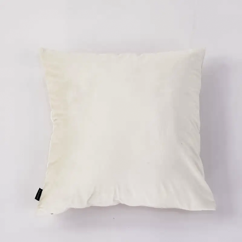 A square off-white throw pillow with a small black fabric tag on the bottom left corner, photographed against a plain white background.