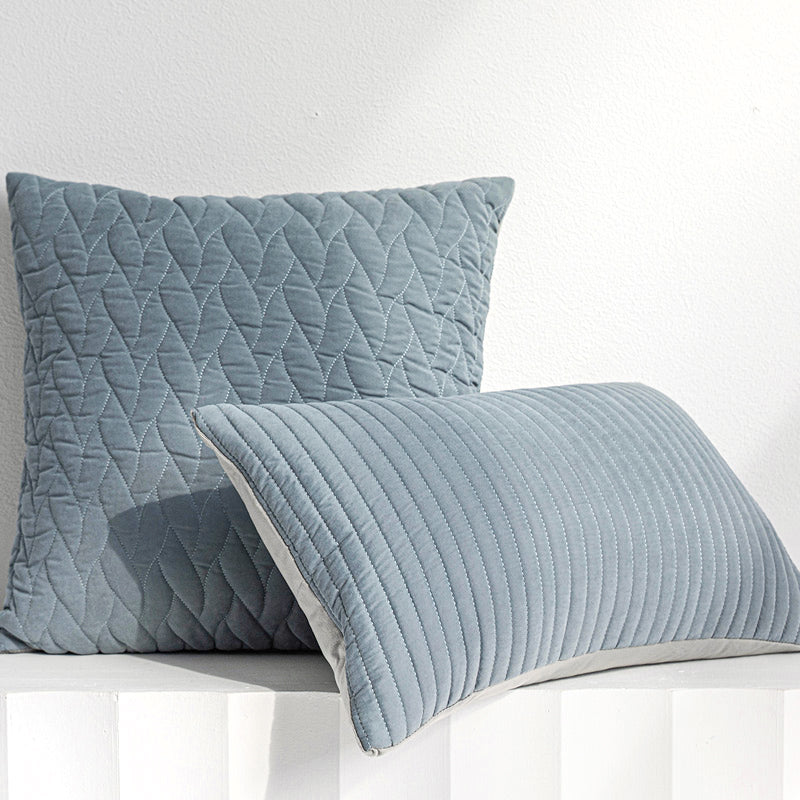 Two quilted blue pillows on a white surface